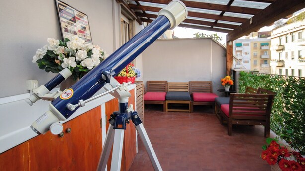 A telescope on a balcony with wooden benches and potted plants. - VivimiHome - Zanella House (Milan)