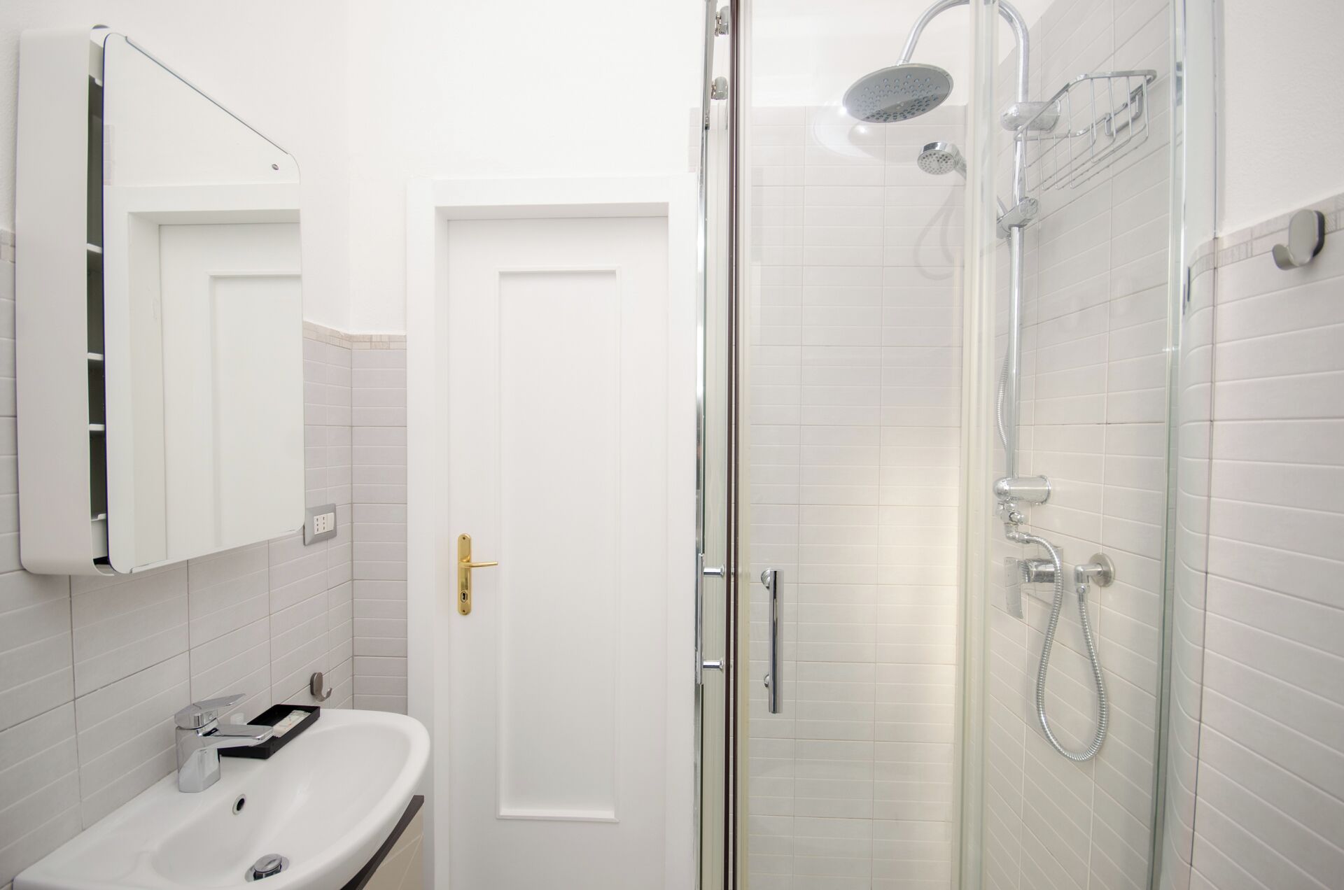 Een badkamer met een witte wastafel, een spiegel en een douchecabine met glazen wanden.