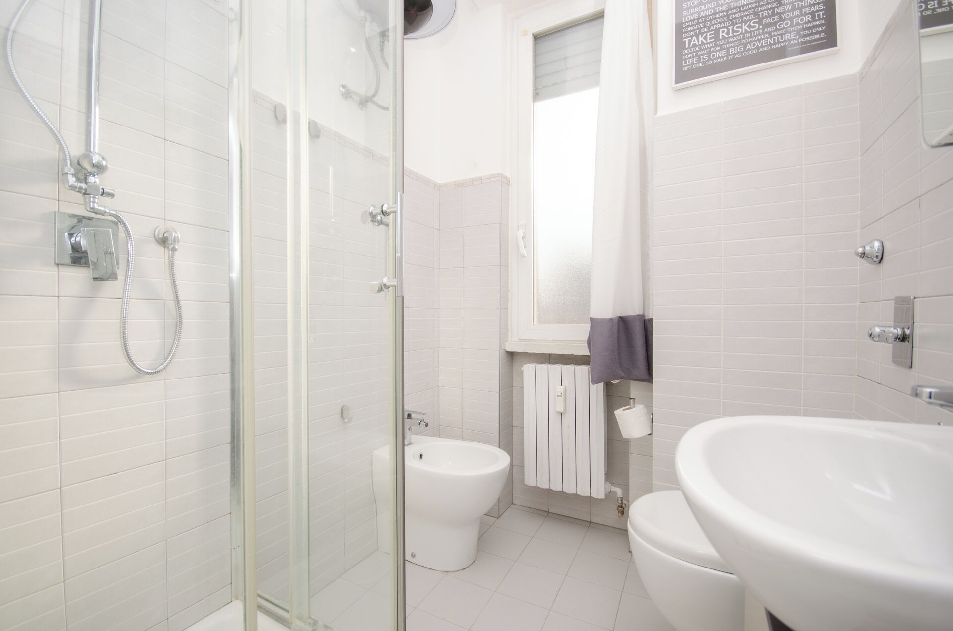 Ein modernes Badezimmer mit Duschkabine aus Glas, Toilette und Waschbecken.