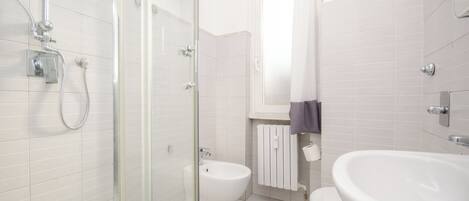A modern bathroom with a glass shower enclosure, a toilet, and a sink.