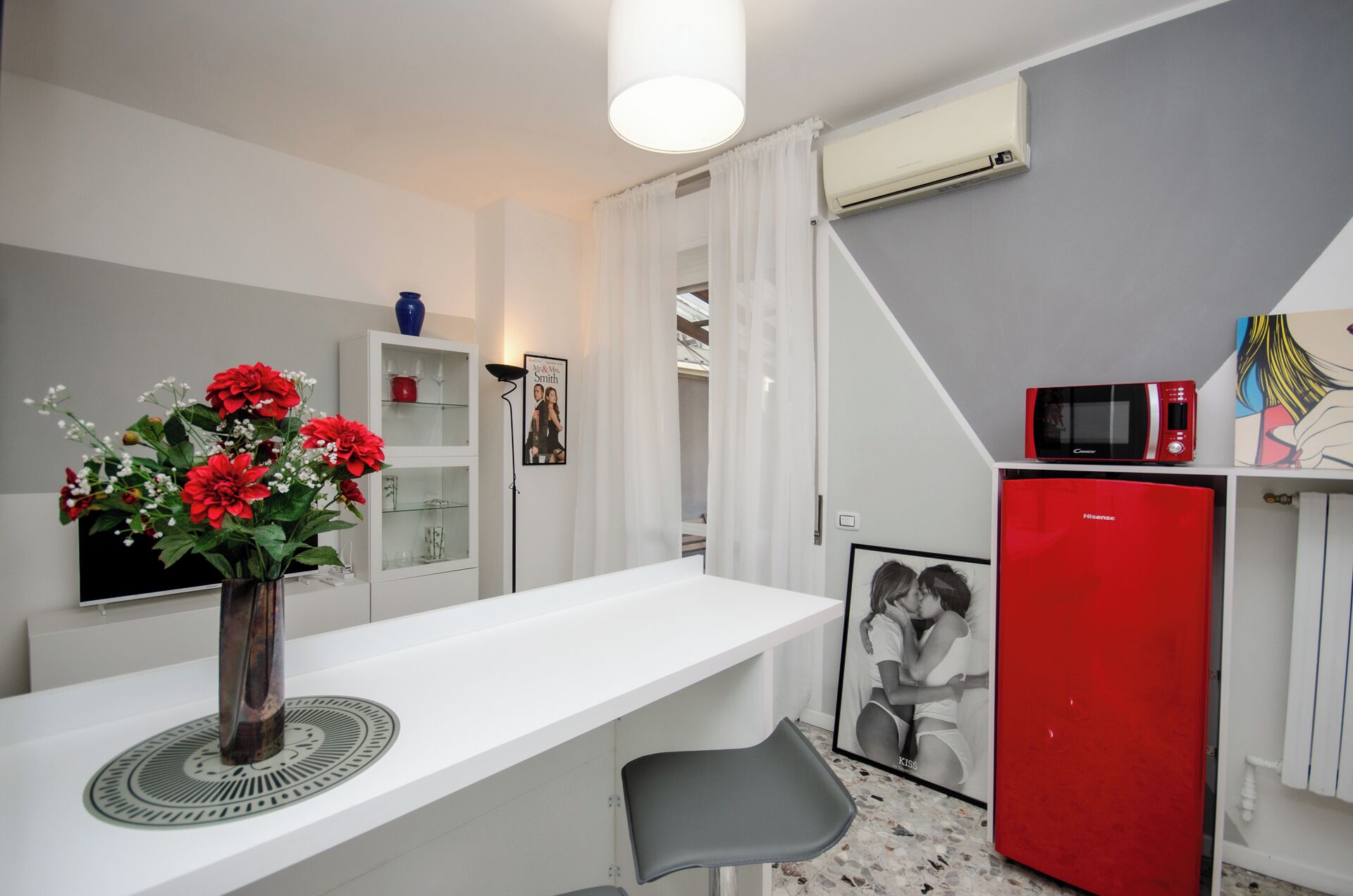 A compact kitchen with a white countertop, a red refrigerator, and a microwave.