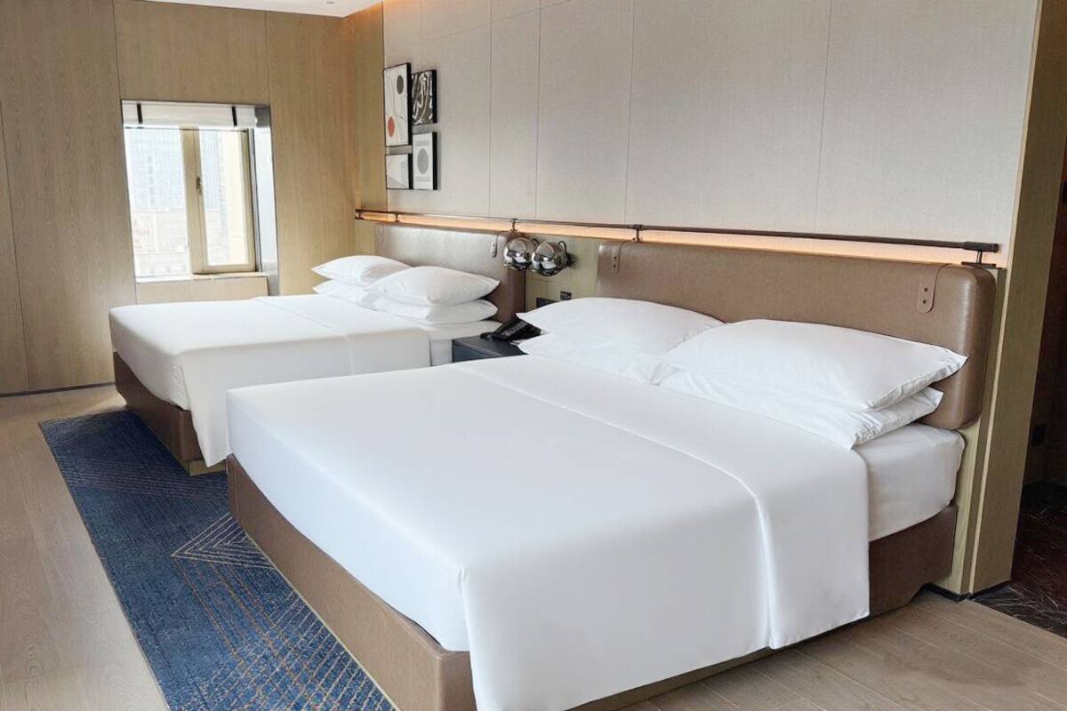 A hotel room with two beds, a desk, and a chair.