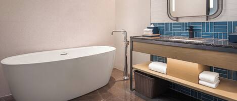 A modern bathroom with a freestanding bathtub, a sink with a mirror, and a towel rack.