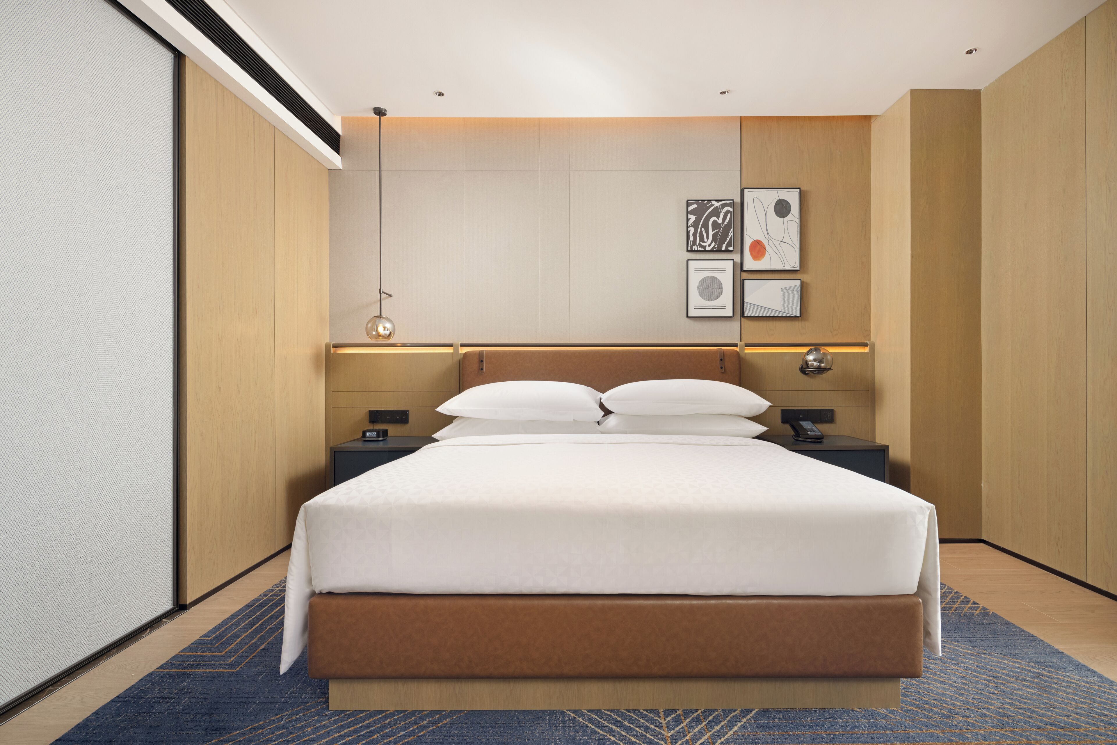 Una habitación de hotel moderna con una cama grande, una mesita de noche y una lámpara fijada a la pared.