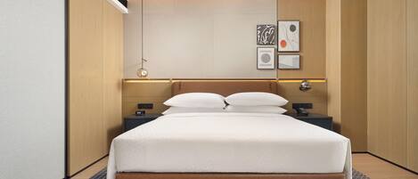 Una habitación de hotel moderna con una cama grande, una mesita de noche y una lámpara fijada a la pared.