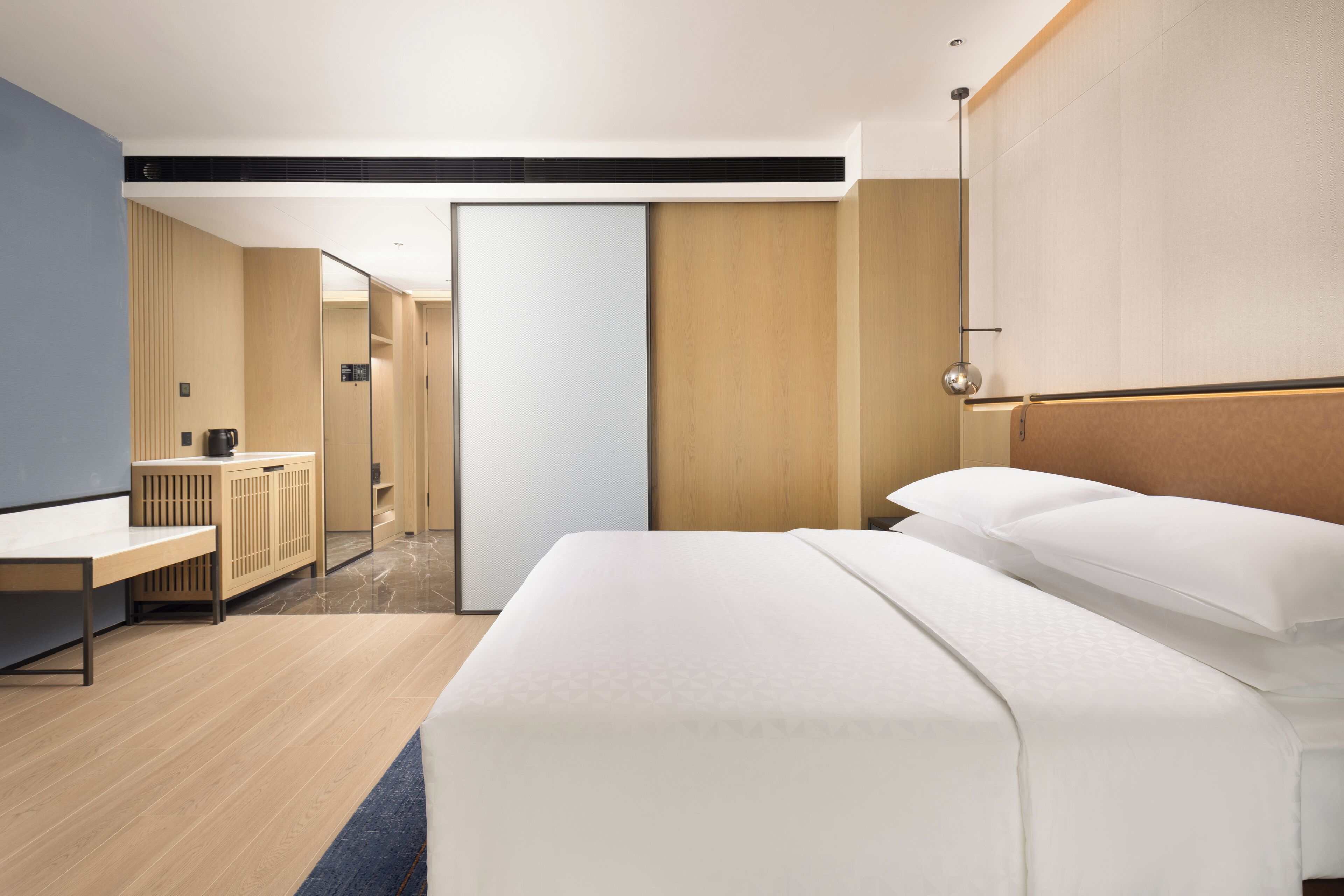 Una habitación de hotel moderna con una cama grande, un escritorio y un armario.
