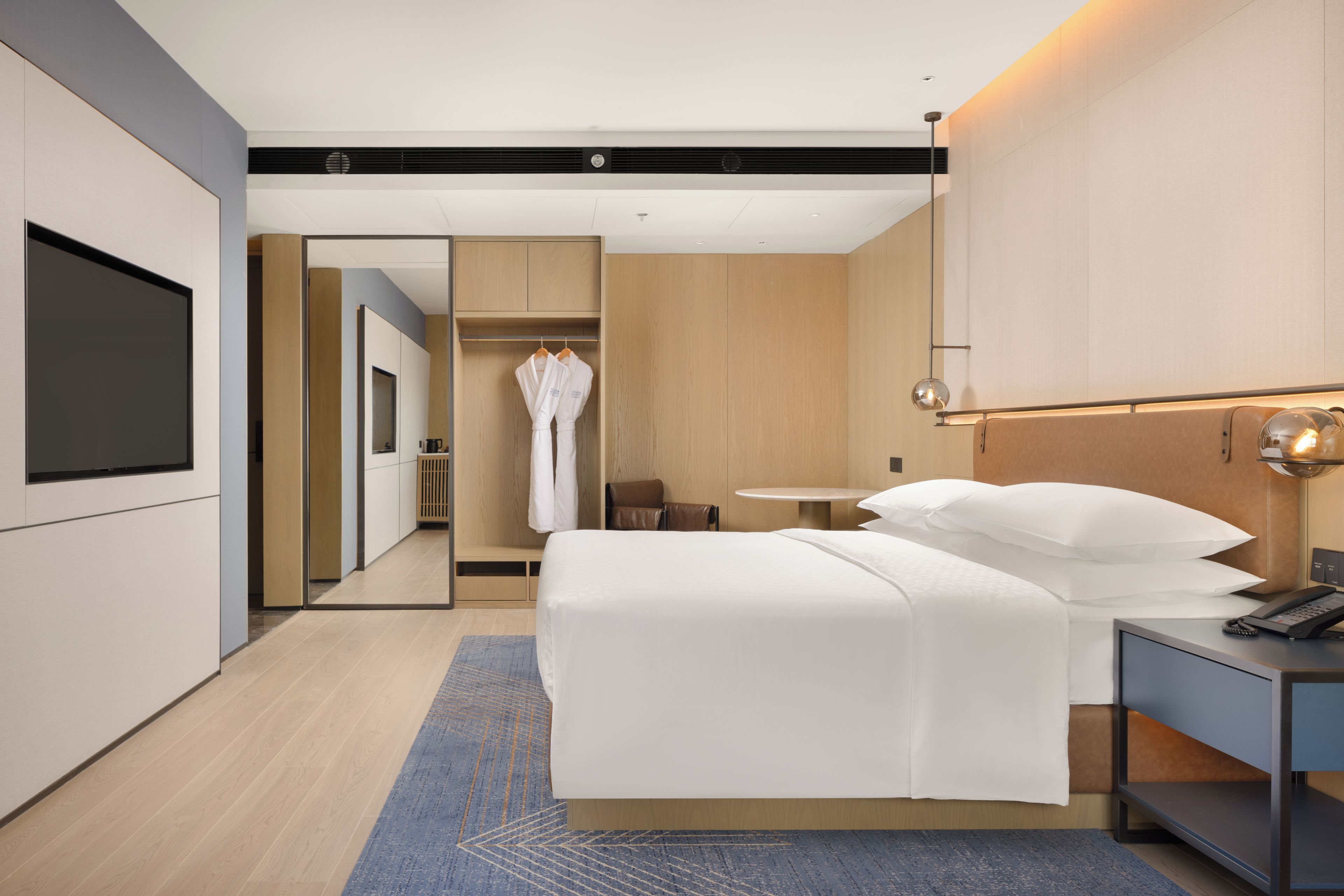 A hotel room with a bed, bedside table, and a mirror.