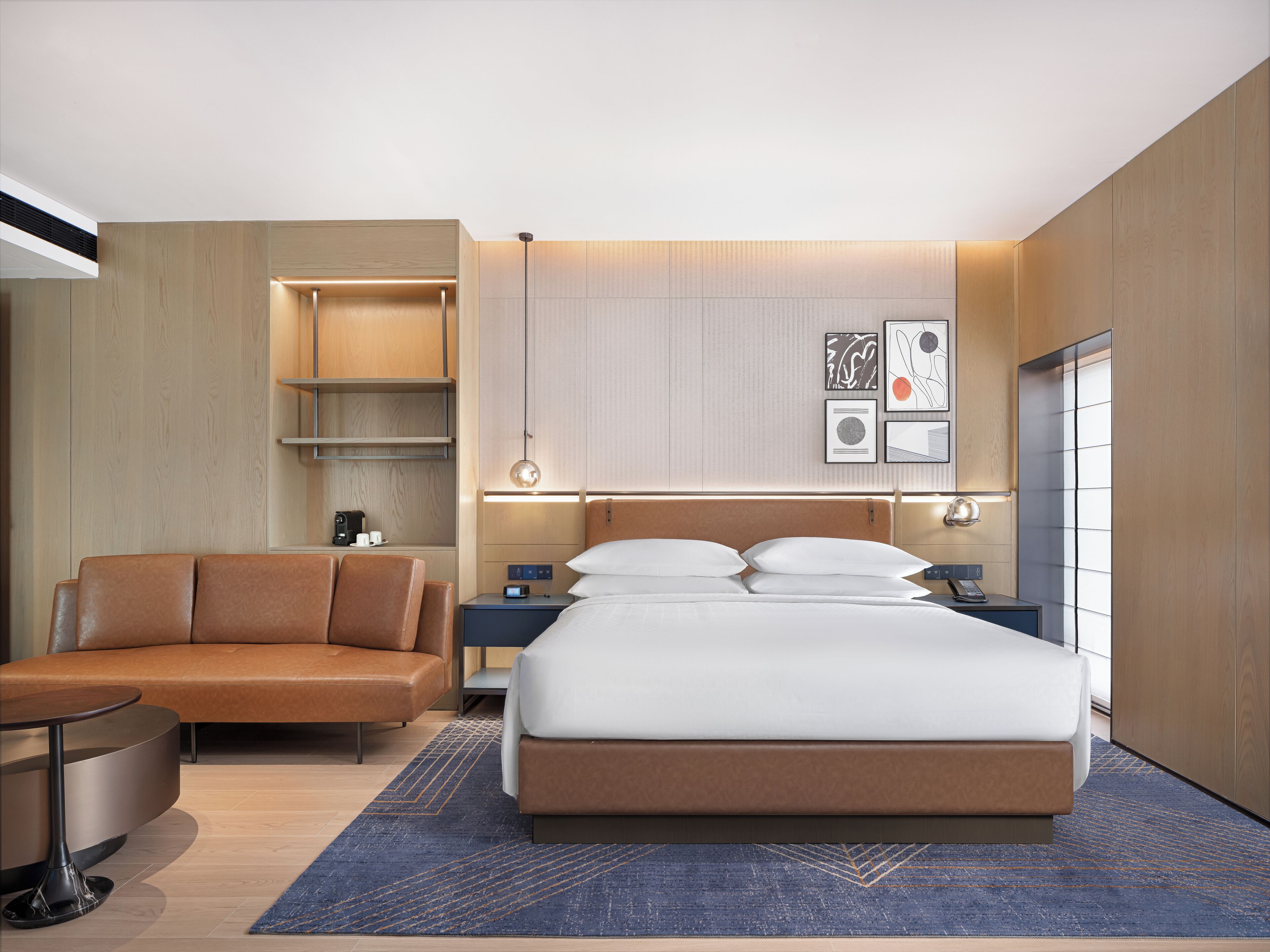 Una habitación de hotel moderna con cama, sofá, escritorio y armario.
