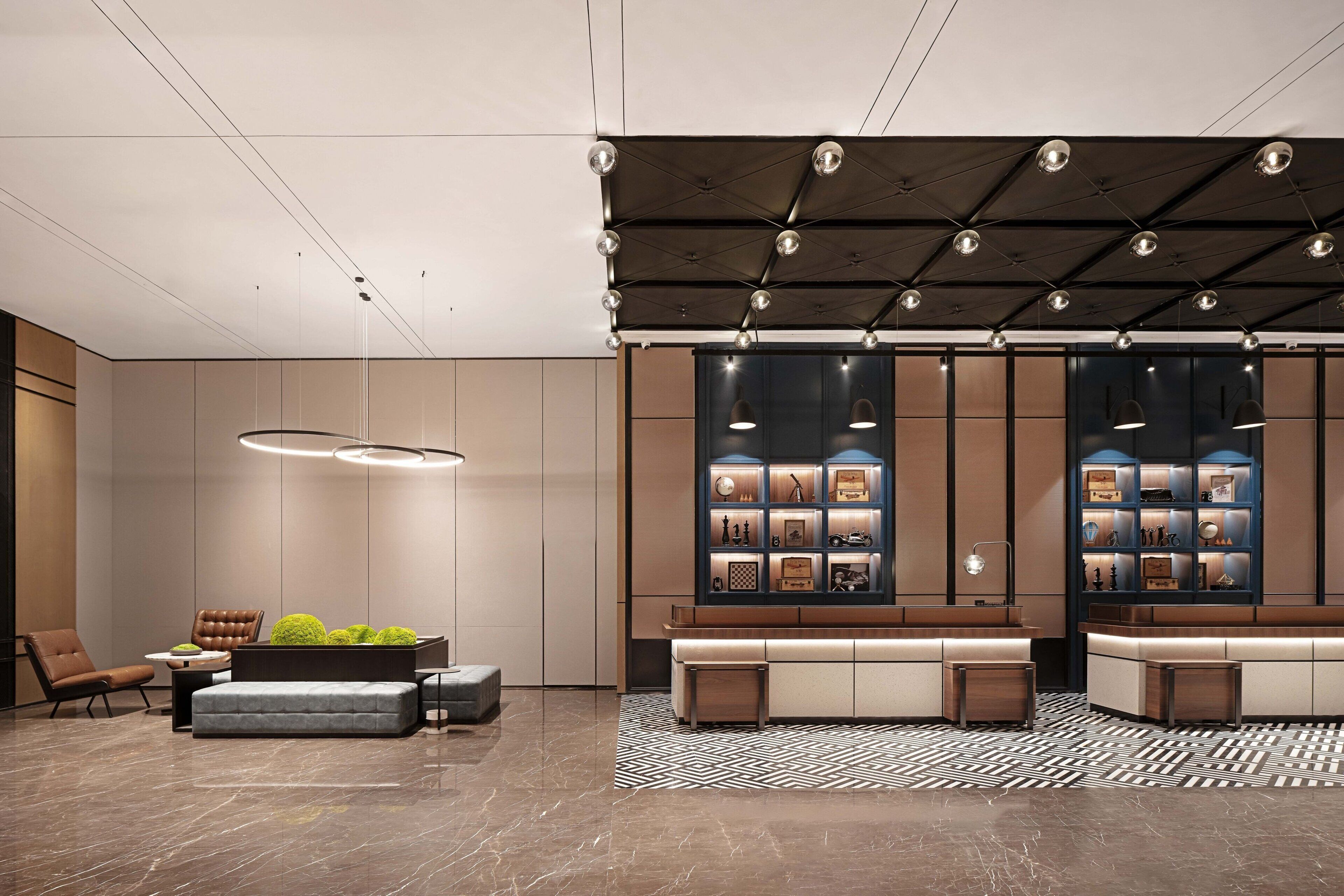 A modern lobby with a seating area, a reception desk, and a display of framed items.
