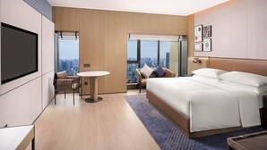 A modern hotel room with a large bed, a desk, a chair, a round table, and a city view through a large window. - Four Points by Sheraton Chengdu, Chunxi Road (Chengdu)