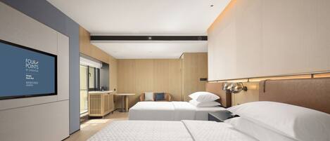 A modern hotel room with two beds, a TV on the wall, and a small table.