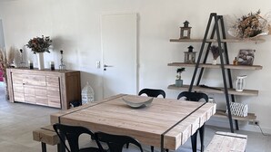 A dining area with a wooden table and chairs, a bench, and a decorative shelf with plants and candles. - Provencal Escape in the Luberon - Villa with Swimming Pool and Mediterranean Garden (Mérindol)