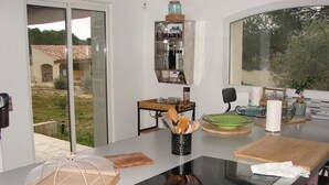 A modern kitchen with a glass-enclosed sliding door, a built-in stove, and various kitchen utensils and appliances. - Provencal Escape in the Luberon - Villa with Swimming Pool and Mediterranean Garden (Mérindol)