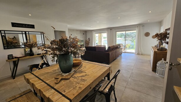 A spacious living area with a wooden dining table, a sofa, and a large window. - Provencal Escape in the Luberon - Villa with Swimming Pool and Mediterranean Garden (Mérindol)