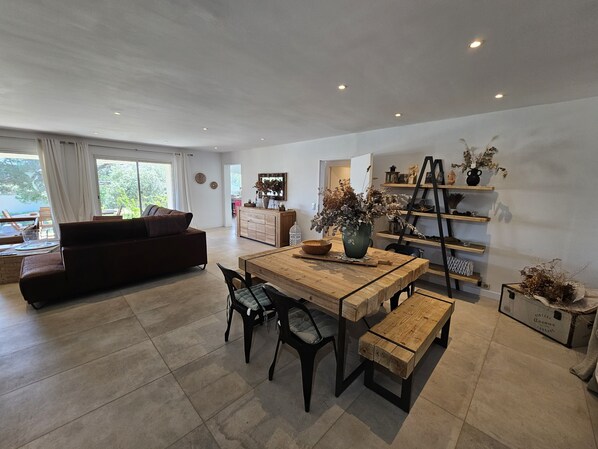 A modern living room with a wooden dining table, a sofa, and a coffee table.