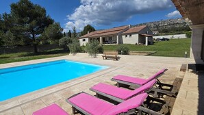 A swimming pool with pink lounge chairs and a house in the background. - Provencal Escape in the Luberon - Villa with Swimming Pool and Mediterranean Garden (Mérindol)