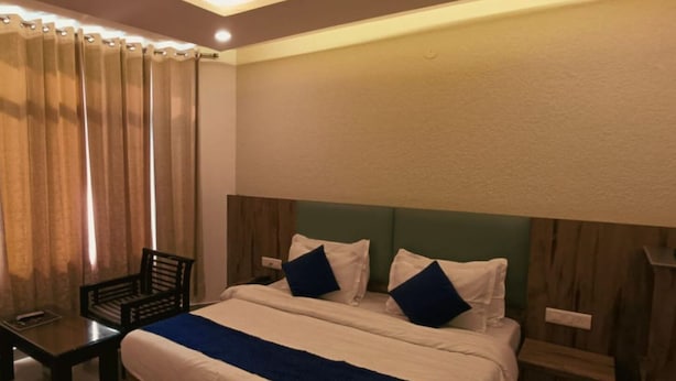 A hotel room with a large bed, two bedside tables, a chair, and a wooden headboard.