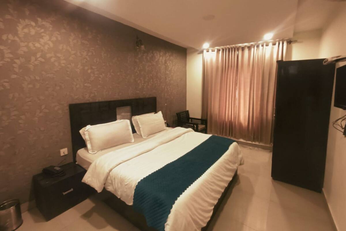 A hotel room with a bed, a nightstand, a wardrobe, and a curtain.