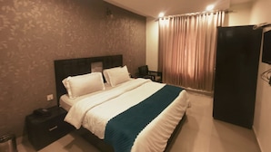 A hotel room with a bed, a nightstand, a wardrobe, and a curtain.