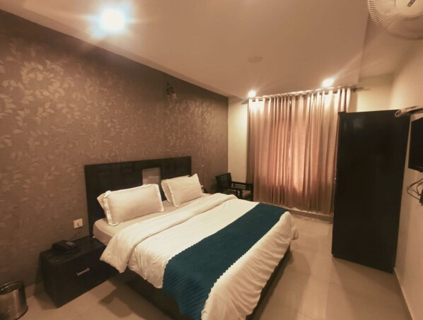 A hotel room with a bed, a nightstand, a wardrobe, and a curtain. - Hotel Wild Rose - Dalhousie (Dalhousie)