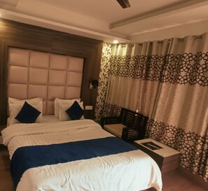 A hotel room with a large bed, a bedside table, a chair, and a patterned curtain. - Hotel Wild Rose - Dalhousie (Dalhousie)