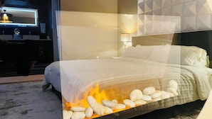 A bedroom with a bed, a nightstand, a lamp, and a television.