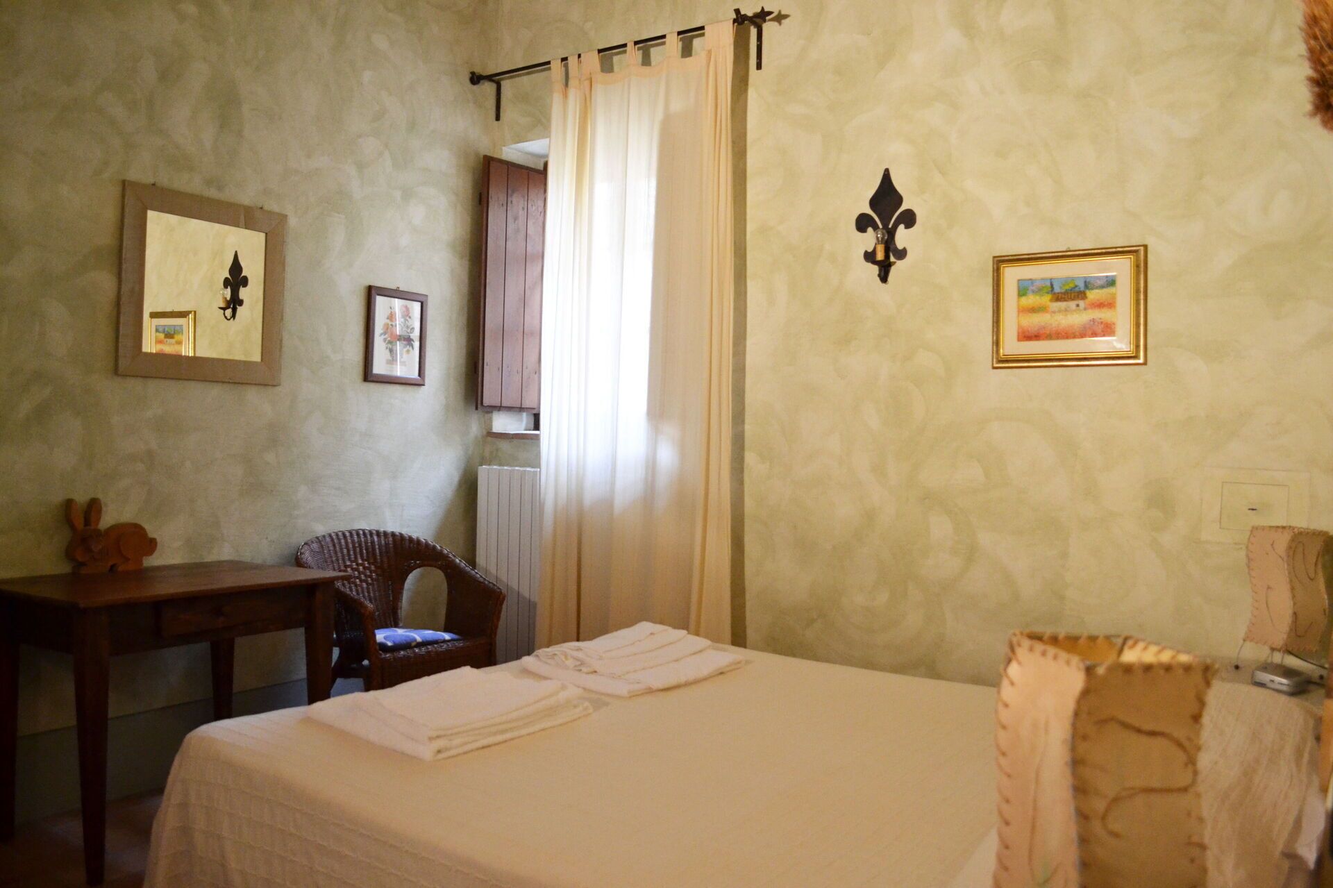 Habitación de hotel con una cama, una silla, una mesita y una ventana con cortinas.