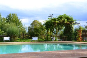 Relax by the serene pool surrounded by lush greenery and mature trees.