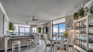 A spacious kitchen with a dining area, large windows, and a view of the ocean.