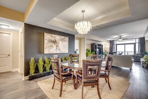A modern dining area with a round table and chairs, a chandelier, and a large abstract painting on the wall.
