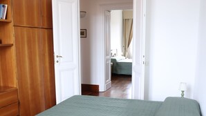 A bedroom with a large bed, wooden wardrobe, and a chair. - DOMUS HORTENSIA AT THE VATICAN (Roma)