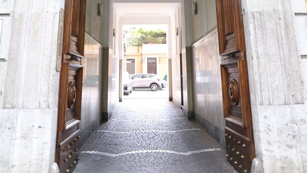 A corridor with a stone floor leading to a wooden door. - DOMUS HORTENSIA AT THE VATICAN (Roma)