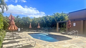 A pool area with lounge chairs and umbrellas, surrounded by palm trees and a clear sky. - Wailea Elua 1304 - Spectacular Oceanfront Condo with Panoramic Views (Wailea, Maui)