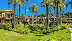 Ein Resort mit mehrstöckigen Gebäuden, Palmen und gepflegten Rasenflächen.