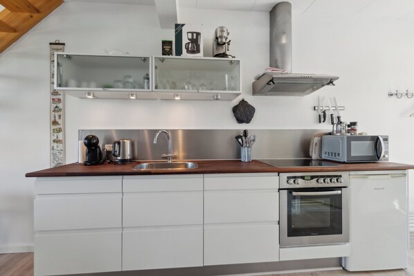 A compact kitchen with a built-in oven, a microwave, and a coffee maker.