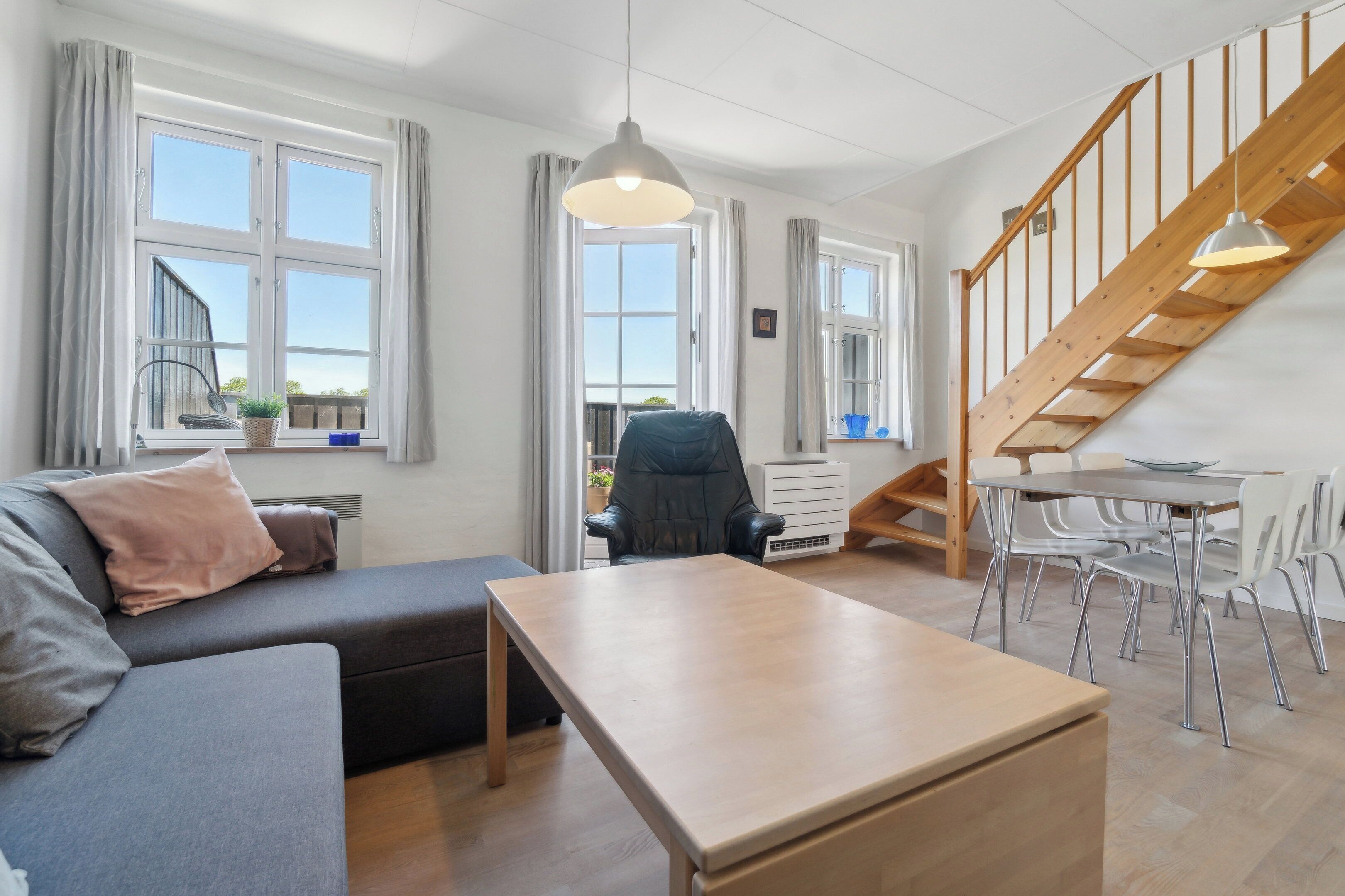 Una sala de estar moderna con un sofá, una mesa, una silla y una escalera.