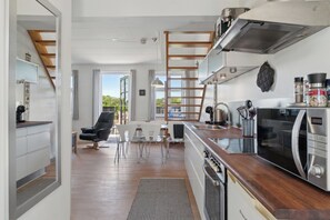 A modern kitchen with a built-in microwave, a wooden ladder, and a view of the outdoors.