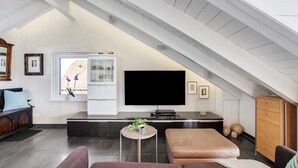 Ein stilvolles Loft-Wohnzimmer mit großem Fernseher, einer Glasvitrine und einer gemütlichen Sitzecke.