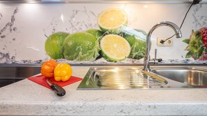 Una cocina con un lavamanos de acero inoxidable, una tabla de cortar roja y un cuchillo.