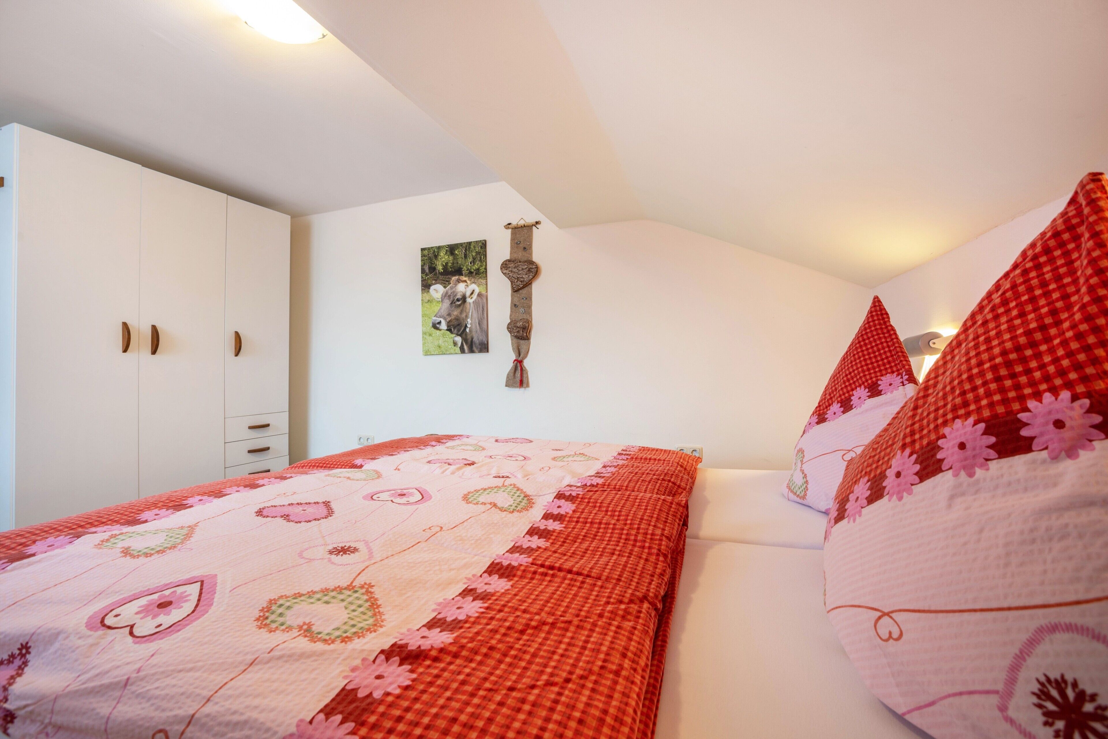 Een slaapkamer met een bed, een witte kledingkast en een aan de muur bevestigd schilderij.