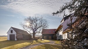 Una propietat rural amb carrerada de grava, un arbre gran i dues cases amb teulades vermelles.