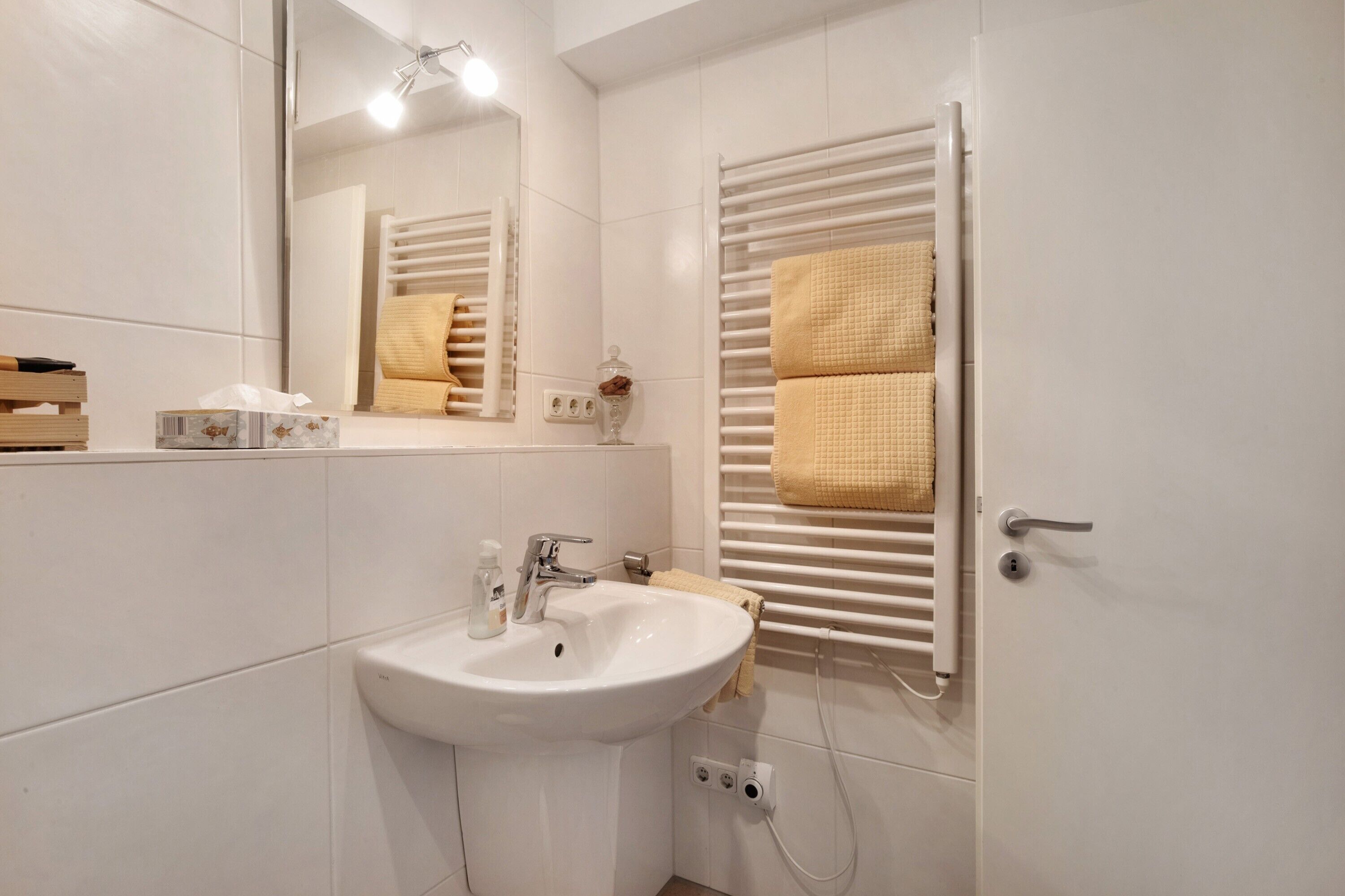 A bathroom with a white sink, mirror, towel rack, and a door.