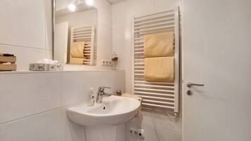 A bathroom with a white sink, mirror, towel rack, and a door.