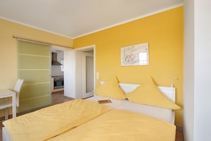 A bedroom with a bed, a chair, a bedside table, and a painting on the wall.