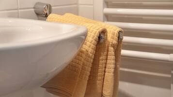 Une salle de bain avec un lavabo blanc, une serviette jaune et un porte-serviettes blanc.