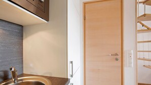 Eine moderne Küche mit Spüle aus Edelstahl, Holzarbeitsplatte und einer Holztür mit Griff.