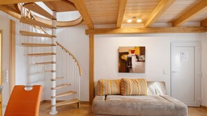 Eine Wendeltreppe, eine Sitzecke mit gestreiften Kissen und ein Essbereich mit einem Stuhl.