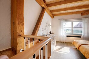 A room with a wooden staircase, a bed, a window with curtains, and a radiator. - Apartment 'Birkethof - Fernblick' with Mountain View, Private Terrace and Wi-Fi (Grimoldsried)