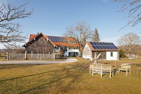 A house with solar panels, a wooden fence, and a bench in the yard. - Apartment 'Birkethof - Fernblick' with Mountain View, Private Terrace and Wi-Fi (Grimoldsried)