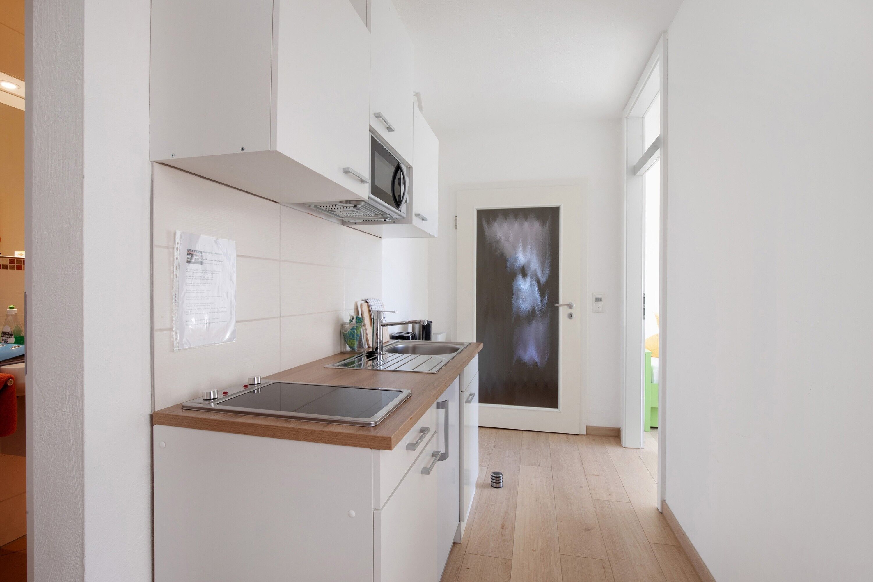 Une cuisine moderne dotée d’un plan de travail en bois, d’un évier en acier inoxydable et d’un four encastré.